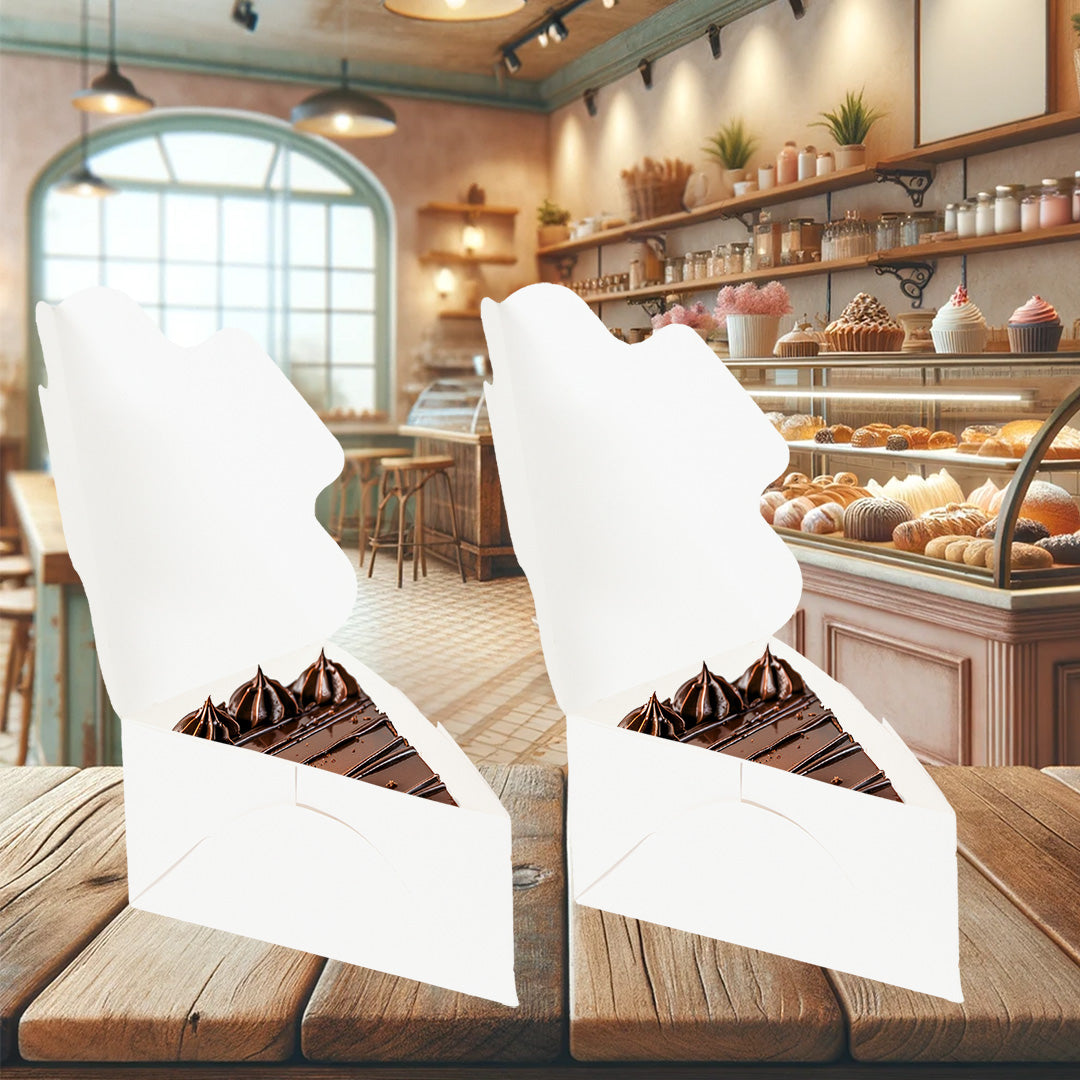 La imagen muestra dos cajas de cartón kraft biodegradable, ambas abiertas, con un trozo de pastel de chocolate en su interior, de fondo una pastelería, cajas practicar y elegantes.