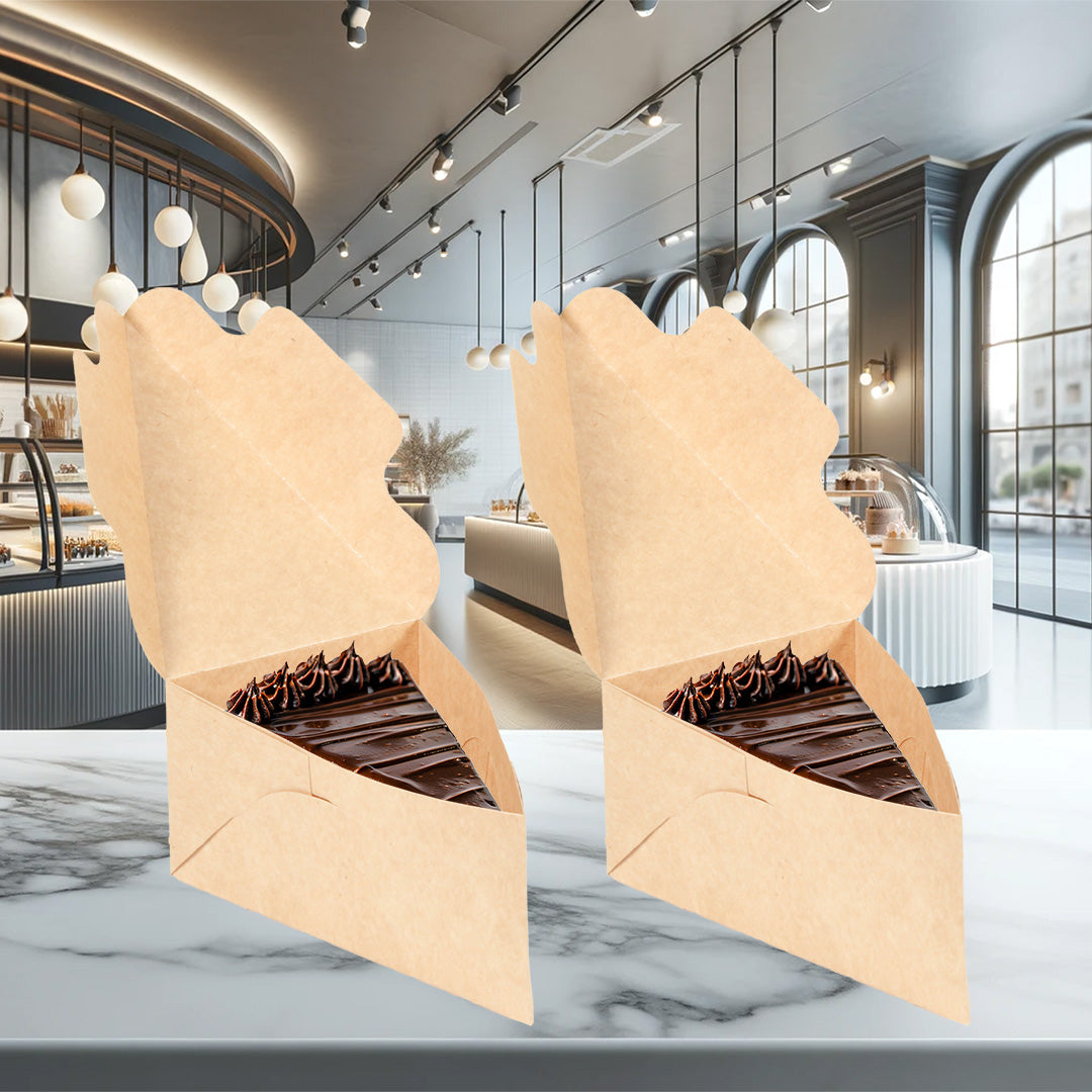 La imagen muestra dos cajas de cartón kraft biodegradable, ambas abiertas, con un trozo de pastel de chocolate en su interior, de fondo una pastelería, cajas practicar y elegantes.