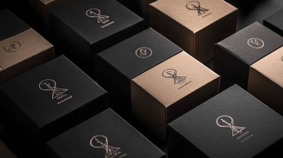 Varios empaques de cartón con diseño minimalista y un sutil acento de color bajo iluminación de estudio.